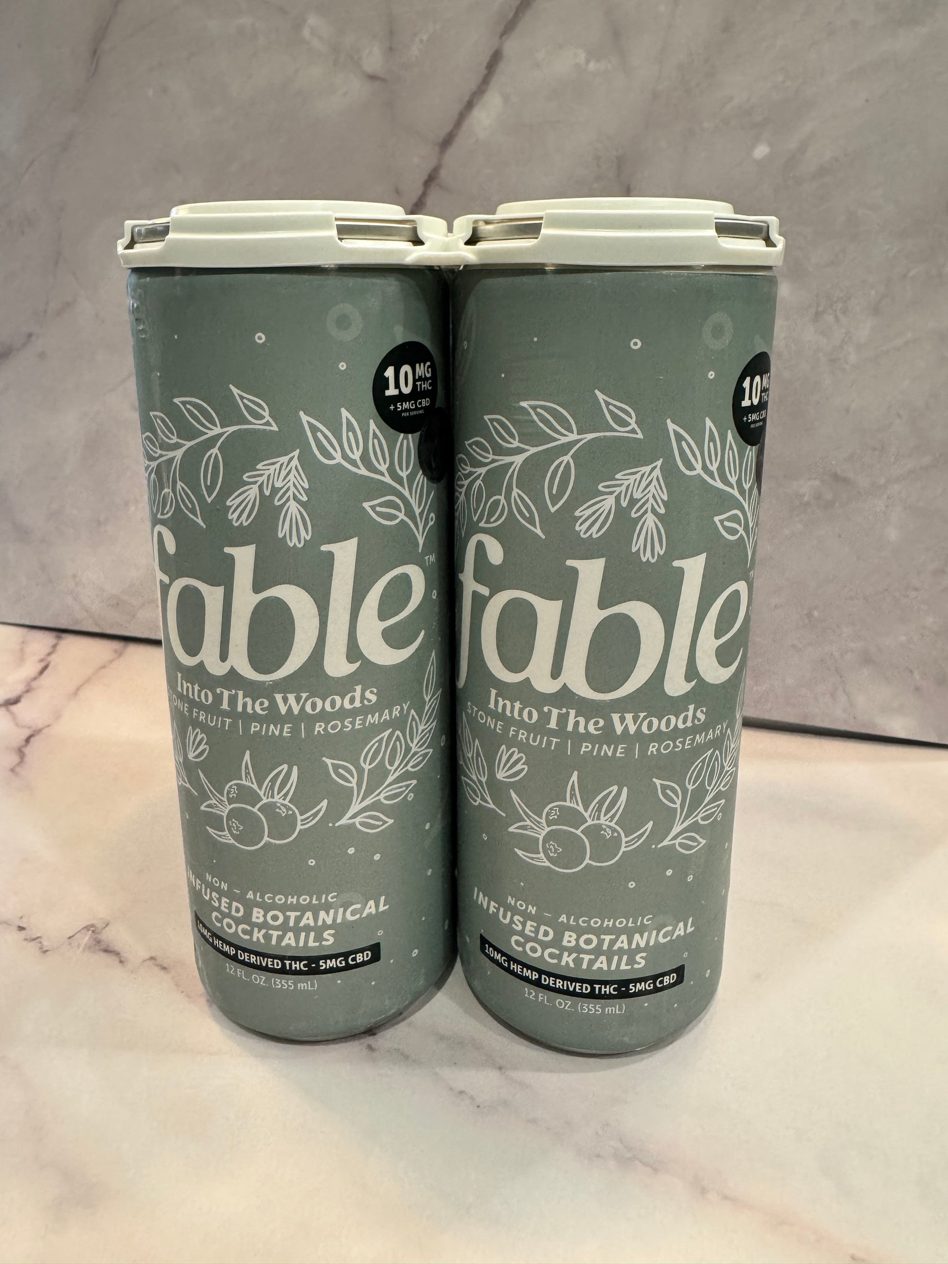 Two gray cans with floral designs and text on a marble surface.